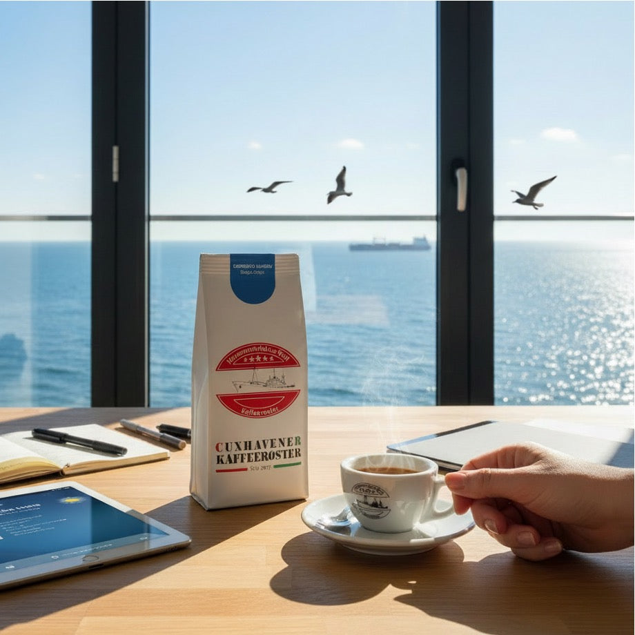 Weiße Kaffeetüte des Cuxhavener Kaffeeroesters mit der Aufschrift Espresso Bugisu auf Schreibtisch und Fenster mit Nordseeblick und frisch gebrühtem Espresso
