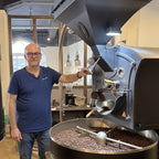 Eigentümer beim Rösten von Kaffeebohnen an Kaffeeröstmaschine