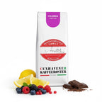 Weiße Kaffeetüte des Cuxhavener Kaffeeroesters mit der Aufschrift Colombia und Aromasymbolen vor weißem Hintergrund