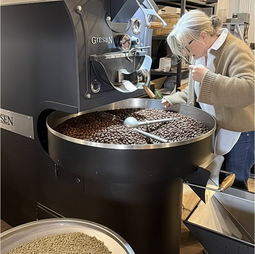 Eigentümerin beim Probenzug an Kaffeeröstmaschine