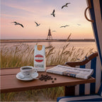 Weiße Kaffeetüte des Cuxhavener Kaffeeroesters mit der Aufschrift Grimmershörner Morgenröte auf Tisch von Strandkorb mit Blick auf die Kugelbake bei Cuxhaven