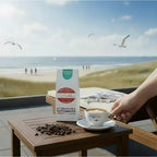 Weiße Kaffeetüte des Cuxhavener Kaffeeroesters mit der Aufschrift Indonesia Ara Mandheling auf Beistelltisch von Strandliege mit Nordseeblick