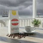 Weiße Kaffeetüte des Cuxhavener Kaffeeroesters mit der Aufschrift Monsooned Malabar auf Veranda mit Blick auf die Nordsee bei Extremwetter