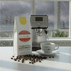 Weiße Kaffeetüte des Cuxhavener Kaffeeroesters mit der Aufschrift Monsooned Malabar auf Küchentheke vor Fenster mit Blick auf die Nordsee bei Extremwetter