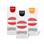 Weiße Kaffeetüten des Cuxhavener Kaffeeroesters eingebunden in Werbung für Unsere Begehrten Vorteilspaket 3x1000g freigestellt vor weissem Hintergrund